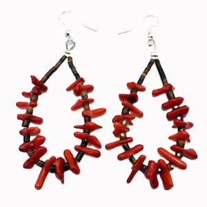 May include: A pair of teardrop-shaped earrings. Each earring features a silver hook, a dark brown beaded section, and a frame of vibrant red coral pieces. The coral pieces are irregularly shaped, adding a natural, organic feel to the jewelry.