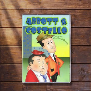 May include: A DVD case featuring the Abbott & Costello comedy duo. The cover art shows cartoon illustrations of the two men, with the title "ABBOTT & COSTELLO" in blue and green lettering. The background is a cityscape with a yellow and green gradient.