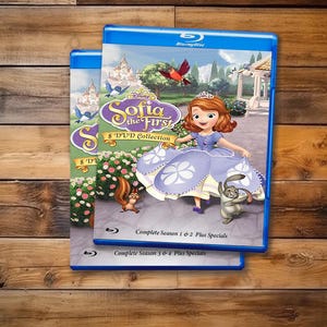 Può includere: Due custodie Blu-ray blu con la collezione di 8 DVD di Sofia the First. La copertina mostra Sofia in un abito viola con un coniglio e uno scoiattolo in un giardino. Il testo include Disney Sofia the First 8 DVD Collection, Complete Season 1 & 2 Plus Specials e Complete Season 3 & 4 Plus Specials.