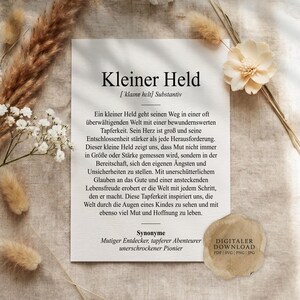 May include: A white rectangular print featuring the German text Kleiner Held, which translates to Little Hero, followed by a definition and synonyms. The print is decorated with dried beige pampas grass and a white flower on a textured fabric.