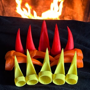 May include: Seven yellow plastic claw-like finger protectors with numbers 6, 8.5, 12, 9.5, and 7.5 printed on them. The protectors are arranged in a row on a black surface.
