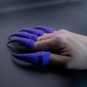 May include: Purple claw-like finger covers for costume or cosplay. The claws are made of a flexible material and are designed to fit over the fingers.