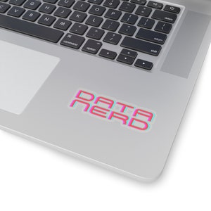 Op de afbeelding: Een sticker met de tekst "DATA NERD" in roze en blauw met een 3D-effect, geplaatst op een zilveren laptop. Het ontwerp van de sticker is opvallend, met een modern lettertype en een speelse uitstraling.