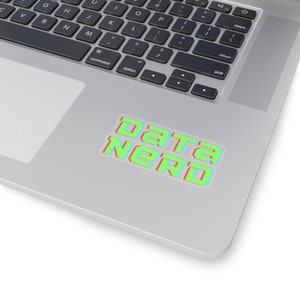 Op de afbeelding: Een sticker met de tekst "DATA NERD" in een gedurfde, futuristische lettertype. De tekst is groen met een rode omlijning, tegen een witte achtergrond. De sticker is geplaatst op een zilveren laptop.