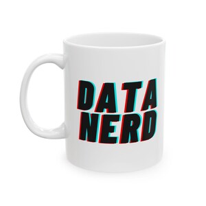 May include: White ceramic mug with the words "DATA NERD" in black, with red and blue shadow effect. The mug has a curved handle and is suitable for hot or cold beverages.
