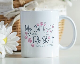 May include: White ceramic mug with a pink cat face and paw prints. The text on the mug reads "My Cat and I Talk Sh*t About You".