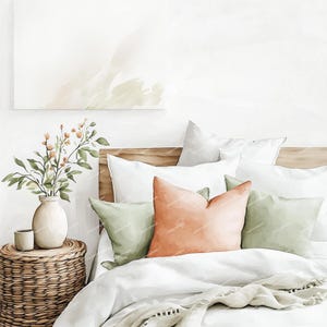 May include: A bedroom scene featuring a bed with white bedding, accented by peach and green throw pillows. A woven side table holds a vase with greenery and a small cup. A painting hangs on the wall above the bed.