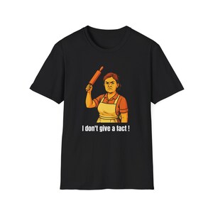 May include: Black t-shirt featuring a cartoon illustration of a woman holding a rolling pin with an angry expression. The woman wears an apron and the text "I don't give a fact!" is below the image.