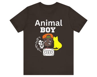 Op de afbeelding: Een bruin T-shirt met de tekst "Animal Boy" in wit. Onder de tekst staat een cartoonillustratie van een jongen met een leeuw en een kat. De jongen draagt een rood shirt, een groen-oranje pet en een wit rechthoekje met het woord "Yep" erin.