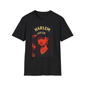 May include: Black t-shirt featuring a graphic of a woman wearing a hat with the word "HARLEM" in gold lettering. The woman has gold hoop earrings and a cross necklace. The artwork has a red and orange color scheme.