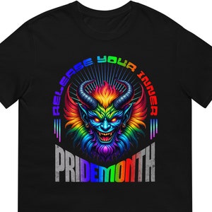 Könnte beinhalten: Schwarzes T-Shirt mit einer farbenfrohen Illustration eines gehörnten Dämons. Der Text "RELEASE YOUR INNER" steht darüber und "PRIDEMONTH" darunter. Der Dämon ist in Regenbogenfarben dargestellt.
