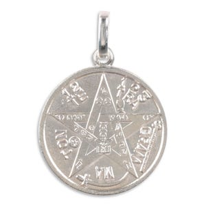 May include: A silver pendant with a pentagram design. The pendant has detailed engravings of symbols and text around the star. It includes a loop at the top for attaching to a chain or cord.
