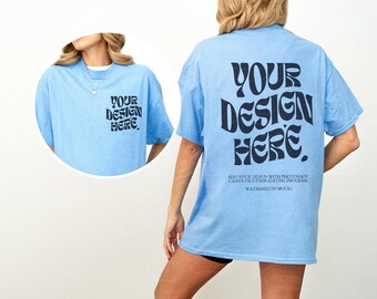May include: A light blue t-shirt featuring dark navy text on the back that reads YOUR DESIGN HERE, with smaller text below. A circular inset shows the front of the shirt with the same text on the chest. The shirt has a crew neck and short sleeves.