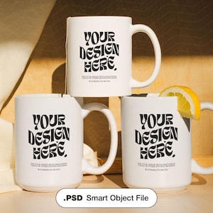 May include: Three white ceramic mugs featuring the black text YOUR DESIGN HERE, with smaller text below reading ADD YOUR DESIGN WITH PHOTOSHOP CANVA OR OTHER EDITING PROGRAM WATERMELON MOCKUP. One mug has a lemon slice on the rim and a tea bag string.
