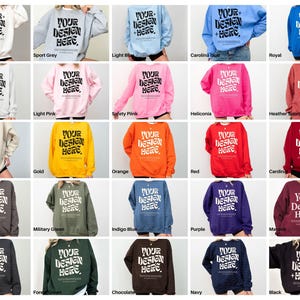 May include: A collection of 20 crewneck sweatshirts in various colours, including white, grey, light blue, Carolina blue, royal blue, ash, light pink, safety pink, heliconia, heather sport scarlet, sand, gold, orange, red, cardinal, charcoal, military green, indigo blue, purple, maroon, dark heather, forest green, chocolate, navy, and black. Each sweatshirt features the text "Your Design Here" in a bold, stylised font.