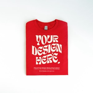 Pu&ograve; includere: Maglietta rossa con testo bianco che dice "YOUR DESIGN HERE. ADD YOUR DESIGN WITH PHOTOSHOP, CANVA OR OTHER EDITING PROGRAM. WATERMELON MOCKS"