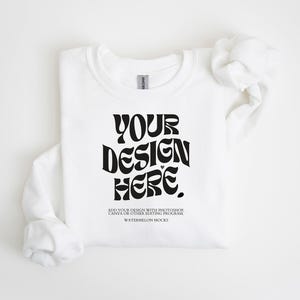 May include: A white crewneck sweatshirt featuring the black text "YOUR DESIGN HERE" in a wavy font, with smaller text below reading "ADD YOUR DESIGN WITH PHOTOSHOP, CANVA OR OTHER EDITING PROGRAM" and "WATERMELON MOCKS" printed on the chest area.