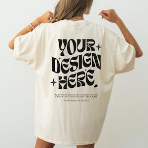 Pode incluir: Uma t-shirt oversize de cor creme com um grande texto preto ondulado nas costas que diz YOUR DESIGN HERE, acompanhado de pequenos ícones de estrelas. Abaixo, um texto preto menor diz ADD YOUR DESIGN WITH PHOTOSHOP, CANVA OR OTHER EDITING PROGRAM. WATERMELON MOCKS.