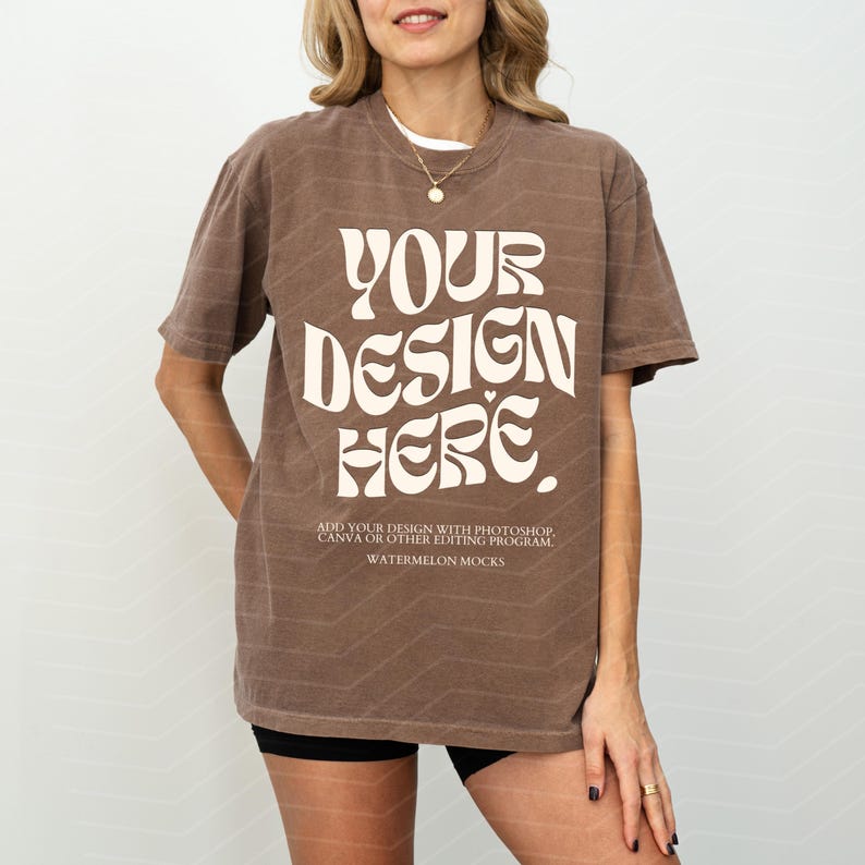 May include: A brown oversized t-shirt with short sleeves and a white graphic that says "YOUR DESIGN HERE. ADD YOUR DESIGN WITH PHOTOSHOP, CANVA OR OTHER EDITING PROGRAM WATERMELON MOCKS".