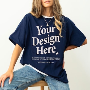 Pode incluir: Uma t-shirt de manga curta azul-marinho com o texto branco Your Design Here, com um texto menor abaixo que diz ADD YOUR DESIGN WITH PHOTOSHOP, CANVA OR OTHER EDITING PROGRAM e WATERMELON MOCKS, usada sobre uma camisola interior branca.