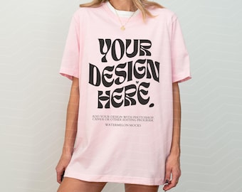 May include: A light pink short-sleeved t-shirt featuring the black text "YOUR DESIGN HERE." and smaller text below reading "ADD YOUR DESIGN WITH PHOTOSHOP, CANVA OR OTHER EDITING PROGRAM, WATERMELON MOCKS" printed on the front of the garment.