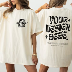 Pode incluir: Uma t-shirt em tom off-white com o texto preto "YOUR DESIGN HERE" numa fonte ondulada no peito e uma versão maior nas costas, acompanhada por pequenos ícones de estrelas e instruções de texto para software de edição digital.