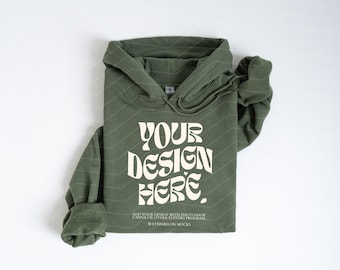 May include: An olive green hooded sweatshirt featuring the white text "YOUR DESIGN HERE" in a bold, wavy font. Below the main text, smaller white text reads "ADD YOUR DESIGN WITH PHOTOSHOP, CANVA OR OTHER EDITING PROGRAM" and "WATERMELON MOCKS".