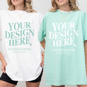 Może przedstawiać: Dwie oversize'owe koszulki, jedna biała, a druga jasnoniebieska, z nadrukiem "YOUR DESIGN HERE" z przodu. Tekst jest w dużej, pogrubionej czcionce. Koszulki są pokazane na modelach.