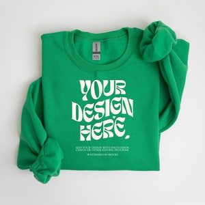 Może przedstawiać: Składana zielona bluza z nadrukiem "YOUR DESIGN HERE." w kolorze białym. Tekst jest w retro stylu czcionki. Tekst pod projektem brzmi "ADD YOUR DESIGN WITH PHOTOSHOP, CANVA OR OTHER EDITING PROGRAM WATERMELON MOCKS."
