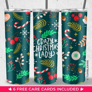 May include: Three stainless steel tumblers with a green background and a Christmas-themed design. The design features red berries, green leaves, snowflakes, candy canes, and a gold ornament. The middle tumbler has the text "Crazy Christmas Lady" in white and gold lettering.