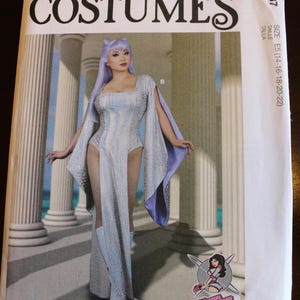 May include: McCall's Costumes pattern featuring a woman in a light blue and white costume with a cape. The costume has a high slit and is paired with matching boots. The pattern includes the size range E5 (14-16-18-20-22).