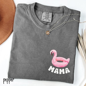 May include: Gray t-shirt with a pink flamingo pool float and the word "MAMA" in white letters.