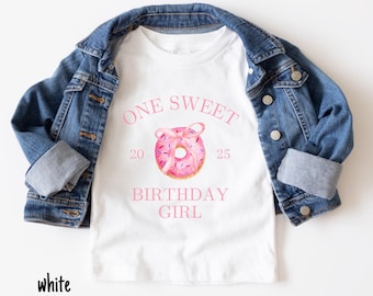 May include: White t-shirt with pink text that reads "One Sweet Birthday Girl" and a pink donut with sprinkles and a pink bow.