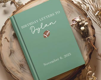 May include: A green hardcover book with the text "BIRTHDAY LETTERS TO Dylan" and a football illustration. The date "November 6, 2025" is printed at the bottom. The book is resting on a wooden surface with dried flowers.