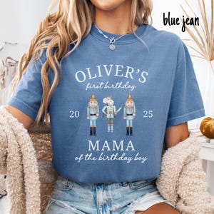 May include: A blue t-shirt with the text "OLIVER'S first birthday" and the words "MAMA of the birthday boy". The shirt features illustrations of a nutcracker, a mouse, and another nutcracker. The numbers 20 and 25 are on either side of the illustrations.