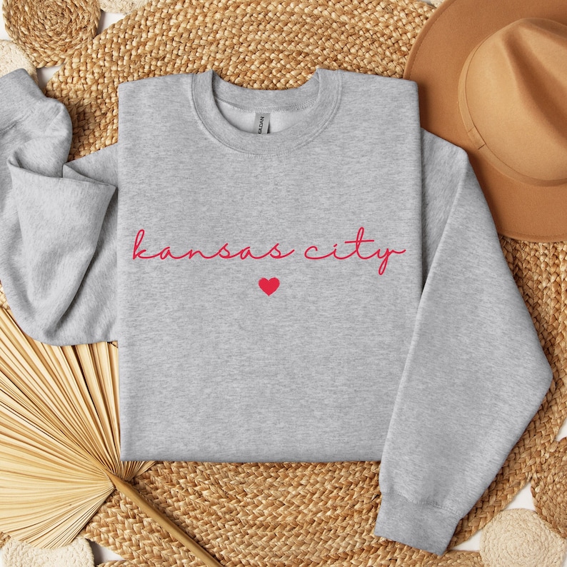May include: Gray sweatshirt with the text "kansas city" in red script with a small red heart below the text.