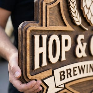 May include: A multi-layered wooden sign featuring a dark brown stained finish with light natural wood accents. The sign displays the text HOP & C BREWING in raised lettering, accompanied by a carved graphic of a hop cone and wheat stalks.