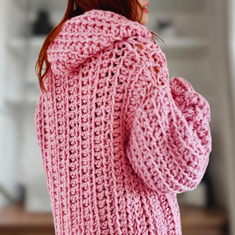 Op de afbeelding: Een roze gebreide cardigan met een capuchon en lange mouwen. De cardigan heeft een losse, oversized pasvorm.