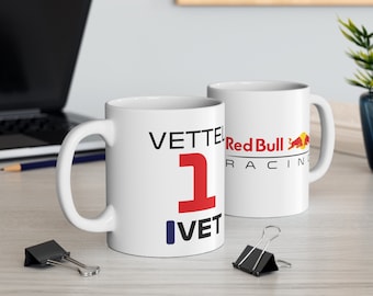 May include: Two white ceramic mugs with a racing theme. One mug features the number "1" in red with the text "VETTEL" and "IVET" in black. The other mug has the Red Bull Racing logo in red and blue.