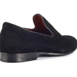 Op de afbeelding: Zwarte su&egrave;de slip-on schoenen met een spitse neus.