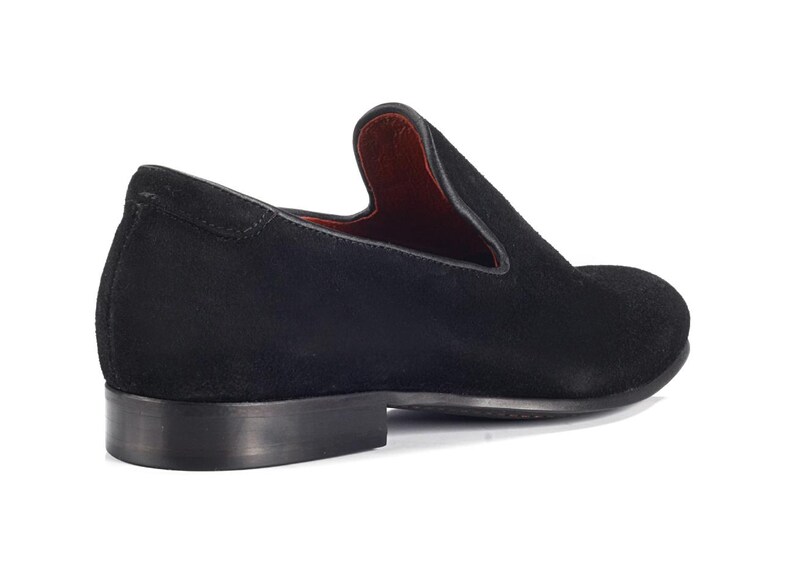 Op de afbeelding: Zwarte su&egrave;de slip-on schoenen met een spitse neus.