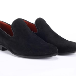 Op de afbeelding: Een paar zwarte su&egrave;de loafers met een spitse neus en een slip-on ontwerp.