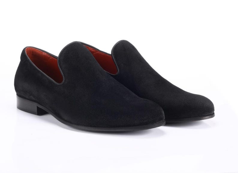 Op de afbeelding: Een paar zwarte su&egrave;de loafers met een spitse neus en een slip-on ontwerp.