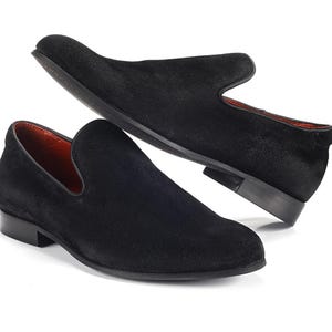 Op de afbeelding: Een paar zwarte su&egrave;de loafers met een spitse neus en een slip-on ontwerp.
