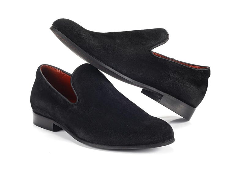 Op de afbeelding: Een paar zwarte su&egrave;de loafers met een spitse neus en een slip-on ontwerp.