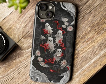 Op de afbeelding: Een zwarte telefoonhoes met een wit en rood bloemenontwerp en witte spookfiguren. De hoes heeft een uitsparing voor de cameralens.