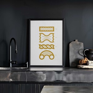 May include: A black framed print with a white background and gold illustrations of different types of pasta. The pasta shapes are labeled with their names.