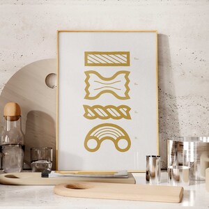 May include: A framed print with a white background and gold illustrations of different types of pasta. The pasta shapes are labeled with their names: Rigatoni, Farfalle, Trofie, and Orecchiette.