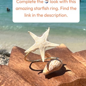 Pu&ograve; includere: Un anello a forma di stella marina con una fascia dorata e una piccola conchiglia. L'anello presenta una grande stella marina bianca e una piccola conchiglia marrone e bianca. Il testo sull'immagine recita: Completa il look con questo fantastico anello a stella marina.