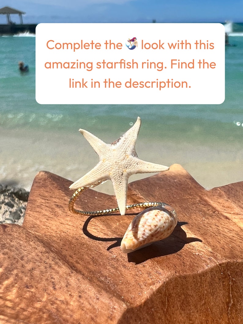 Pu&ograve; includere: Un anello a forma di stella marina con una fascia dorata e una piccola conchiglia. L'anello presenta una grande stella marina bianca e una piccola conchiglia marrone e bianca. Il testo sull'immagine recita: Completa il look con questo fantastico anello a stella marina.